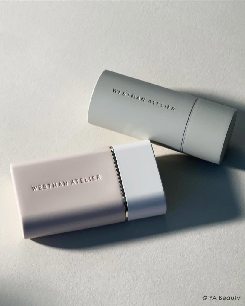 Photograph of Westman Atelier Vital Skincare Complexion Drops and Baby Cheeks Blush Stick in dramatic lighting, set against a clean, gray background.